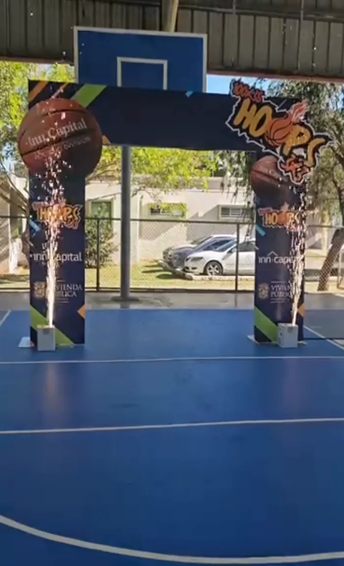 Dos máquinas de chispa fría disparando bajo un arco de entrada en una cancha bajo techo